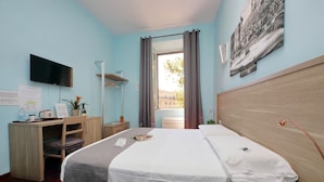 A hotel room with a bed, desk, chair, TV, and a window with curtains. - New Moon (Rome)