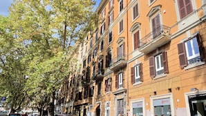 A row of multi-story buildings with balconies and storefronts, including a visible 'Gabbett' sign. - New Moon (Rome)