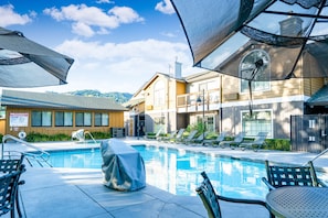 Relax by the pool surrounded by lounge chairs and umbrellas, with scenic views of the hilly landscape.