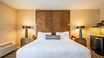 A hotel room with a large bed, bedside tables, a heater, a sink, and a mirror.