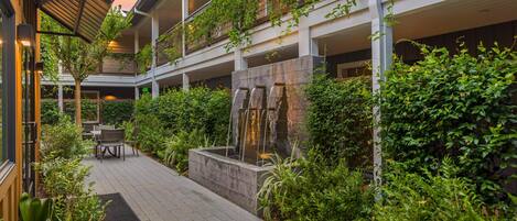A courtyard with a water feature, seating area, and lush greenery.