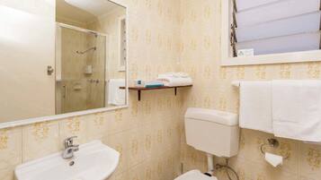 A bathroom with a sink, toilet, and a shower area.