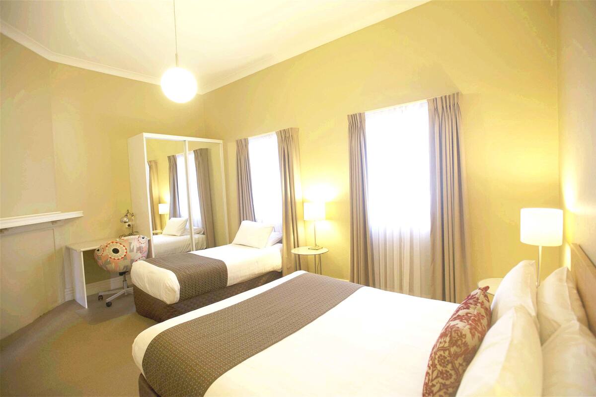 A hotel room with two beds, a desk, a chair, and a mirror.