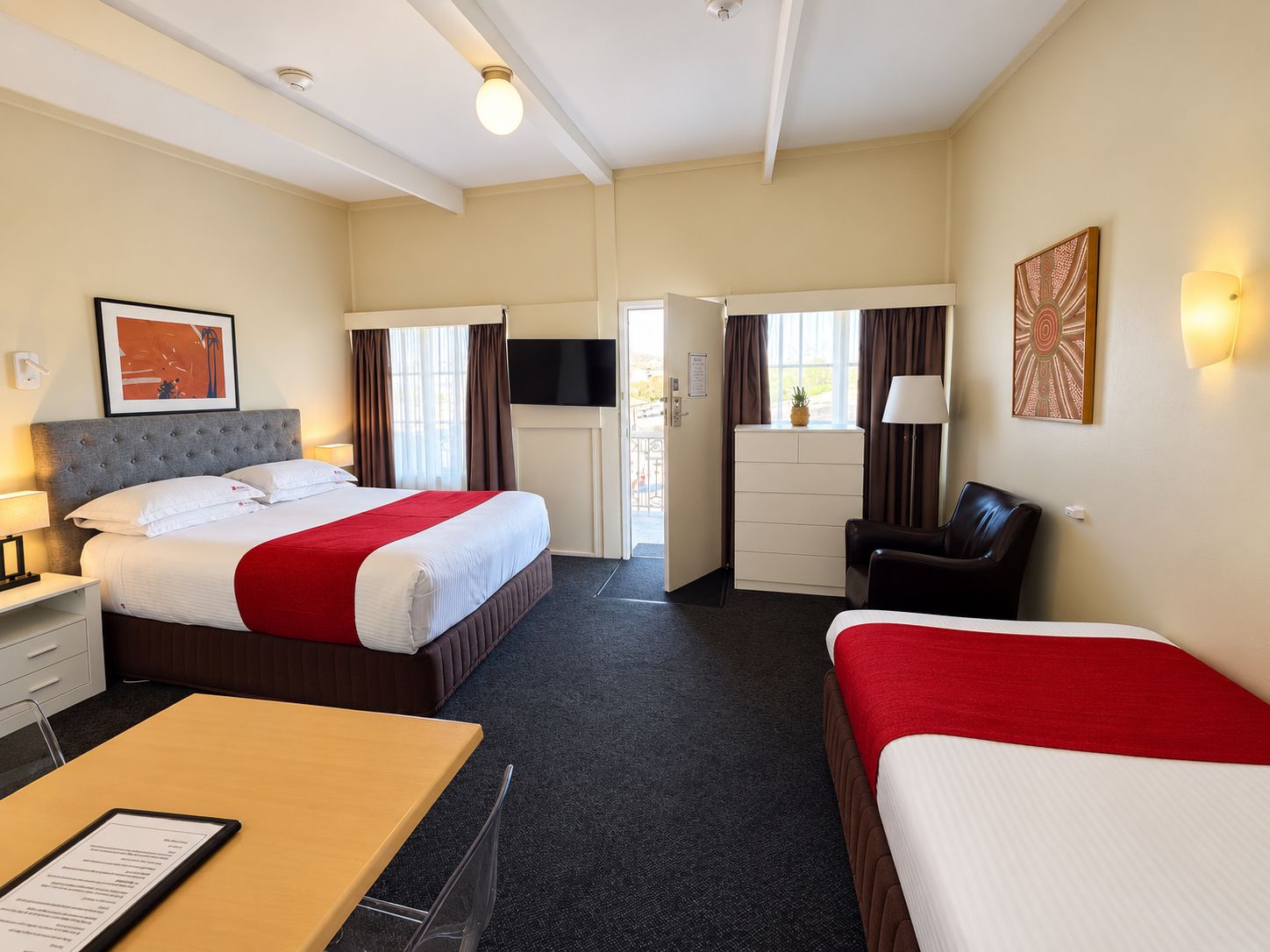 Een hotelkamer met een bed, een bureau, een stoel, een televisie en een dressoir.