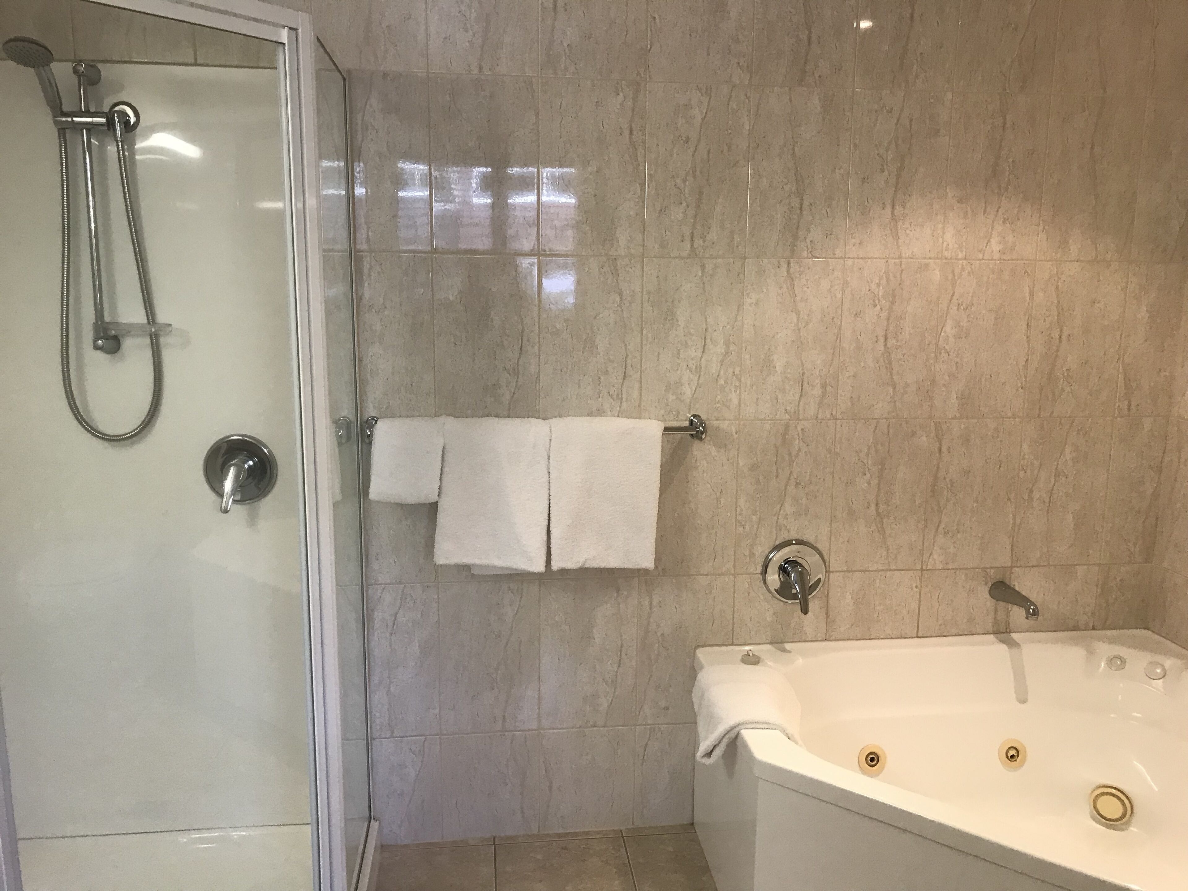 Een aparte badkuip en douche, een bubbelbad, een regendouche