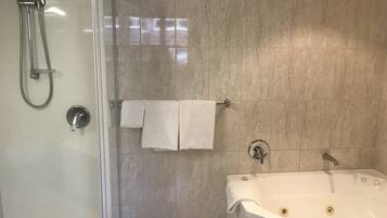 Een aparte badkuip en douche, een bubbelbad, een regendouche