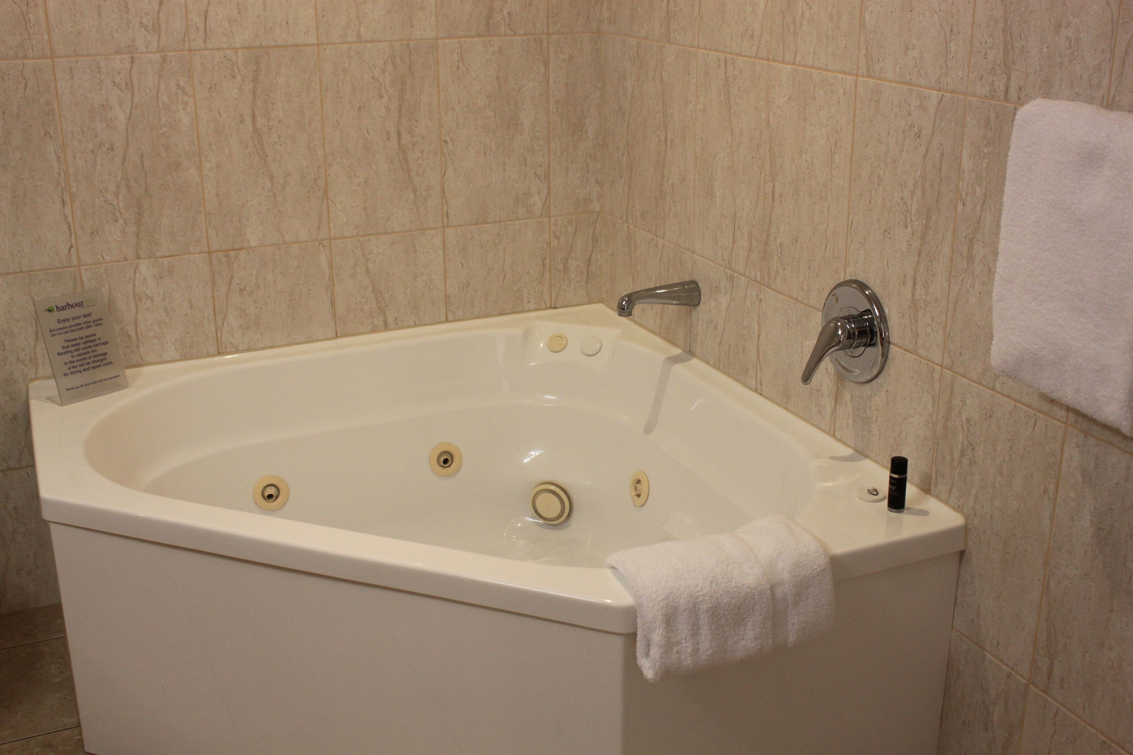 A white bathtub with a single faucet, a small bottle, and a sign on the left.