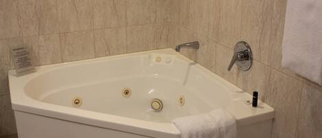 A white bathtub with a single faucet, a small bottle, and a sign on the left.