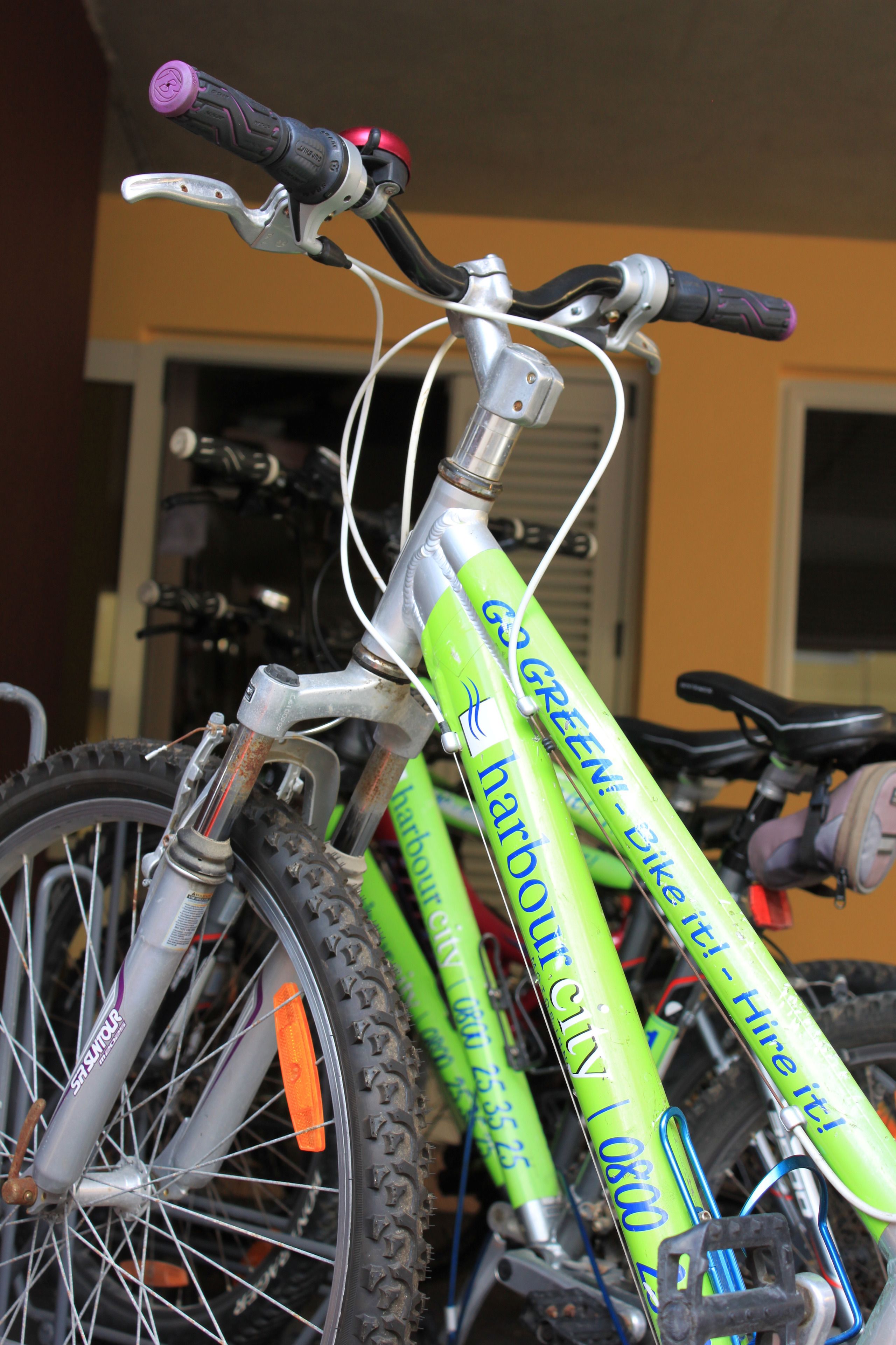 Gros plan d’un vélo vert portant la marque « Harbour City », avec son guidon et un porte-bagages à l’arrière.