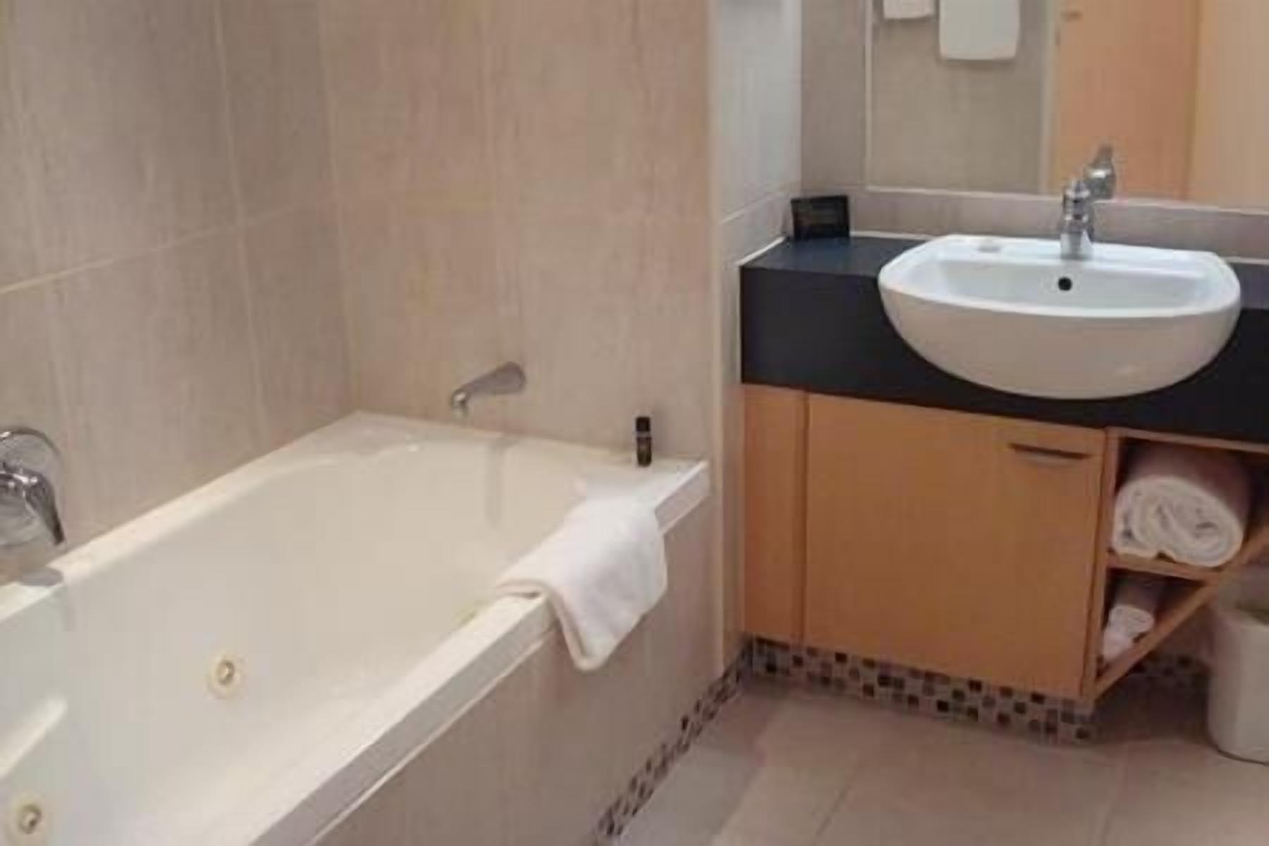 A bathroom with a bathtub, a sink, and a mirror.