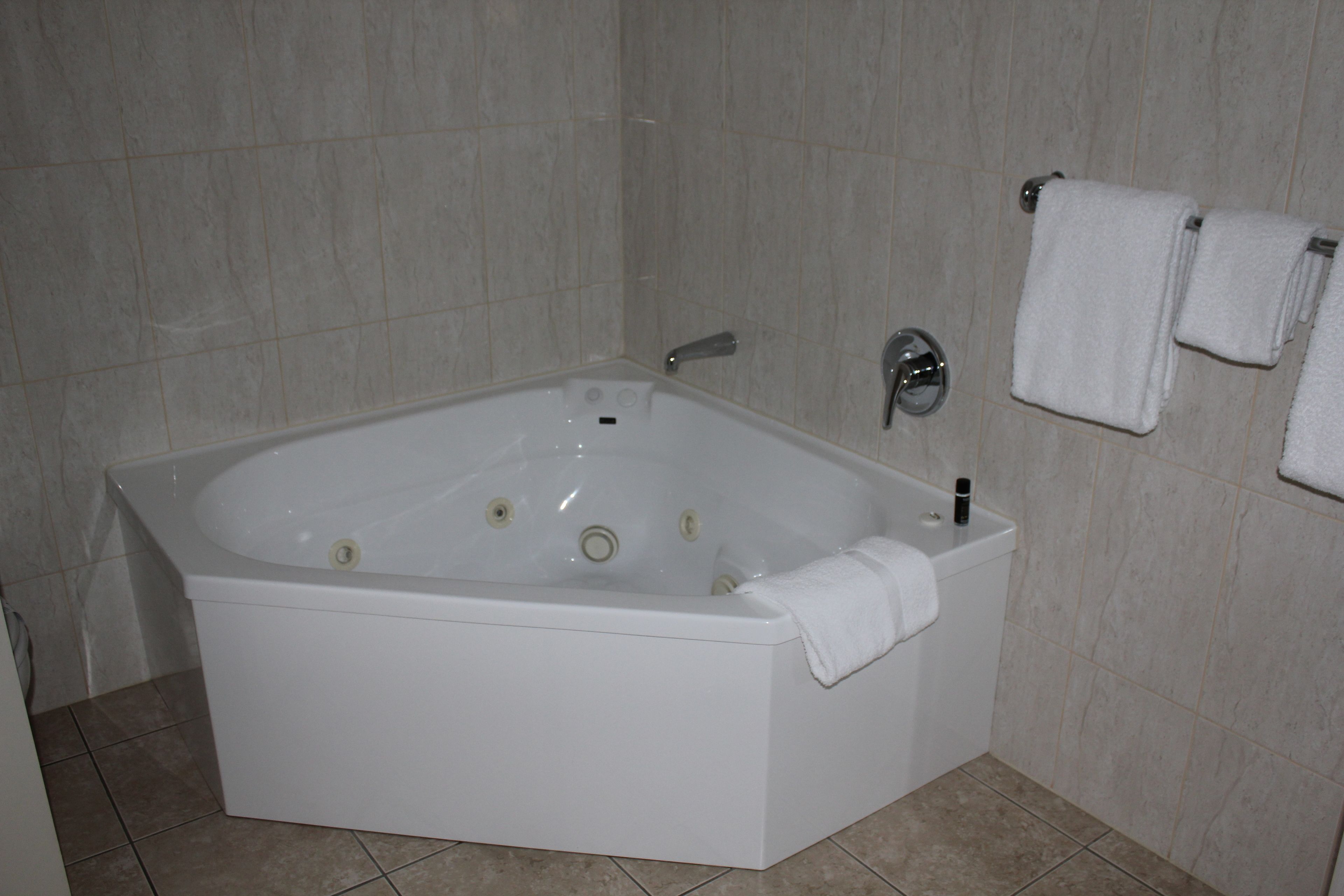 Une salle de bain moderne avec une baignoire sur pieds, des toilettes et un porte-serviettes avec deux serviettes.
