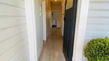 A hallway with white siding, a dark door, and a potted plant.