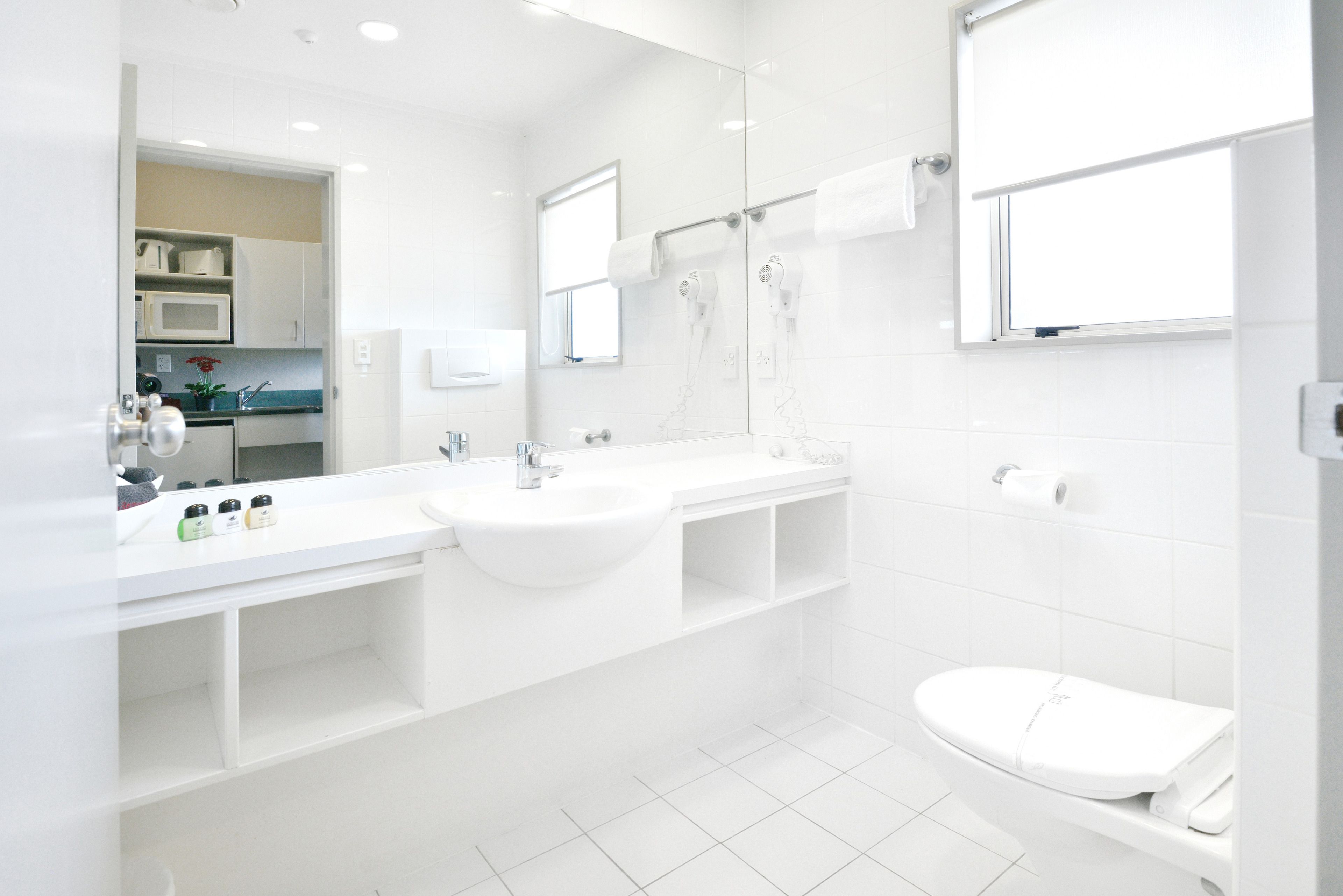 A modern bathroom with a double sink, a toilet, and a shower area.