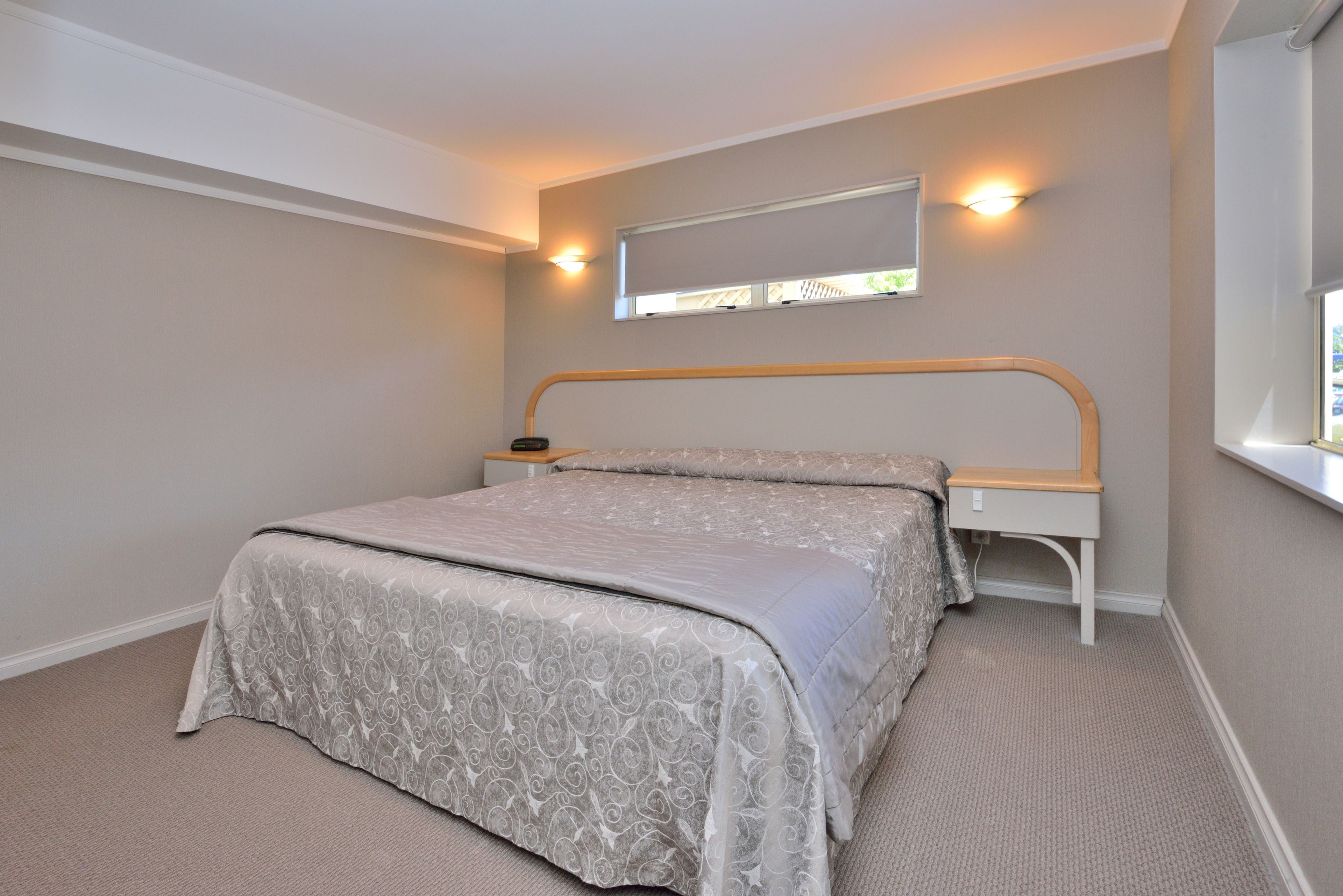 A bedroom with a bed, bedside table, and a window.