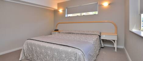 A bedroom with a bed, bedside table, and a window.