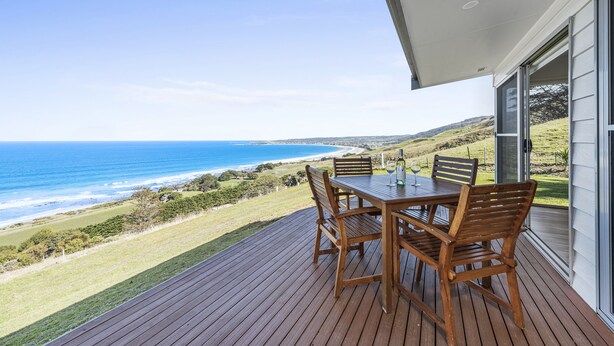 A wooden deck with a table and chairs overlooking a coastal landscape. - Seafarers Getaway (Apollo Bay)