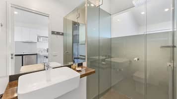 A modern bathroom with a glass-enclosed shower, a large sink, and a wooden countertop.