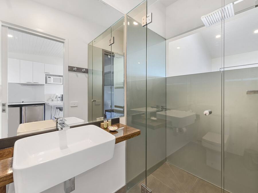 A modern bathroom with a glass-enclosed shower, a large sink, and a wooden countertop.
