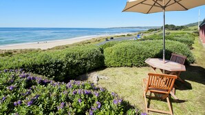 A patio with a table and chairs, overlooking a beach and ocean. - Seafarers Getaway (Apollo Bay)
