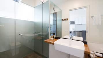 A modern bathroom with a glass shower enclosure, a wooden countertop, and a large mirror.
