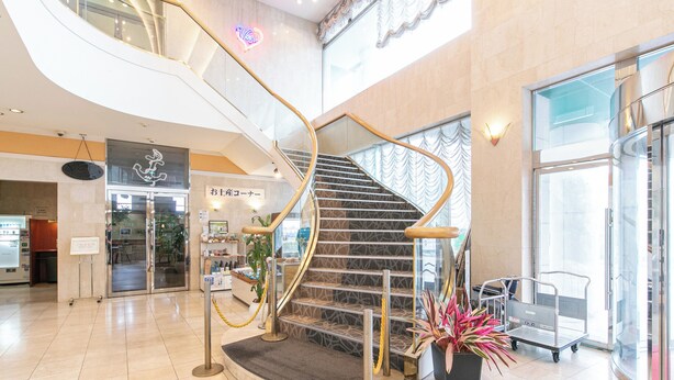 A modern interior with a curved staircase, a reception desk, and a vending machine. - Hotel Verfort Hyuga (Hyuga)