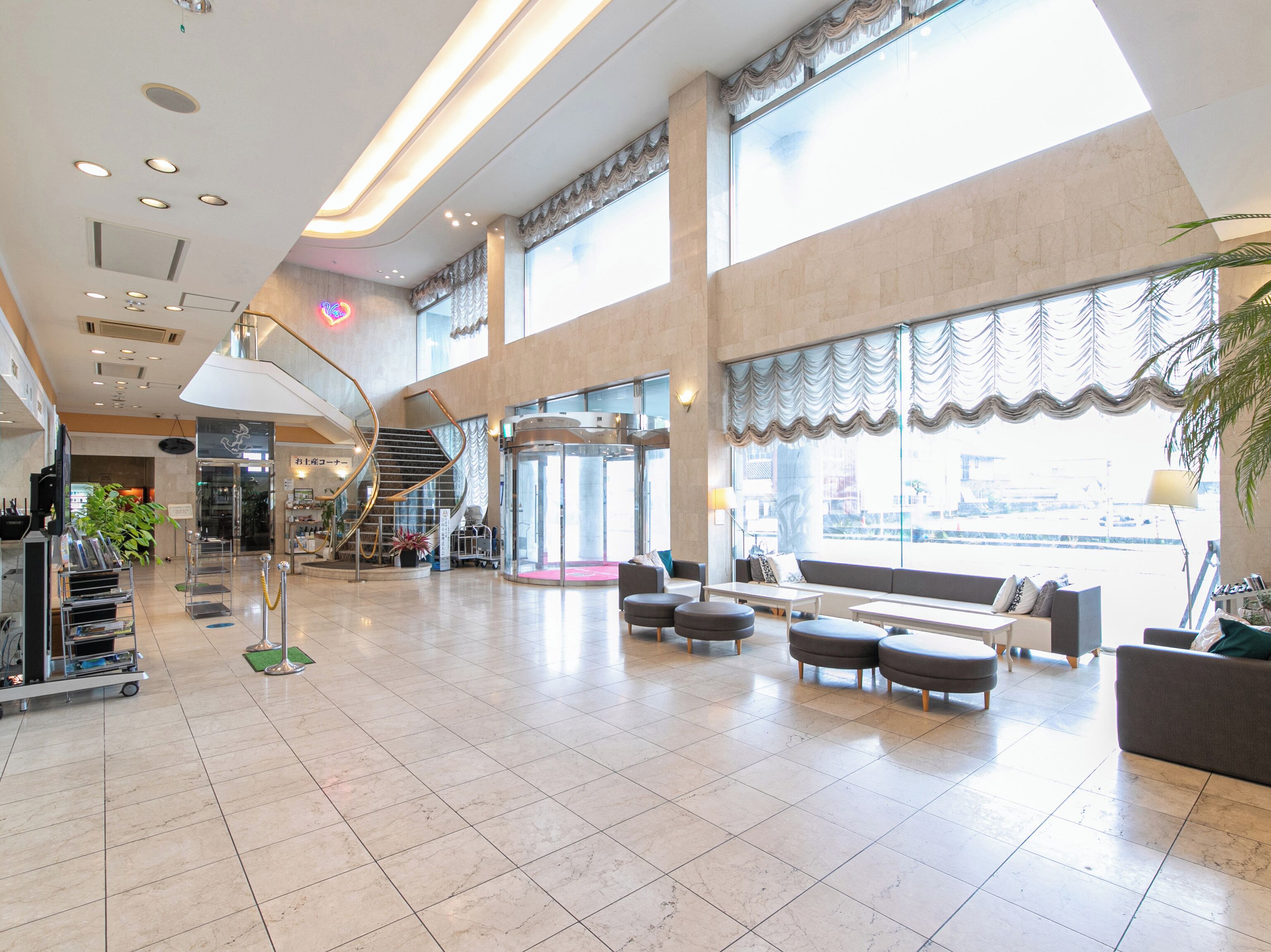 A spacious lobby with a central staircase, seating area, and a reception desk.