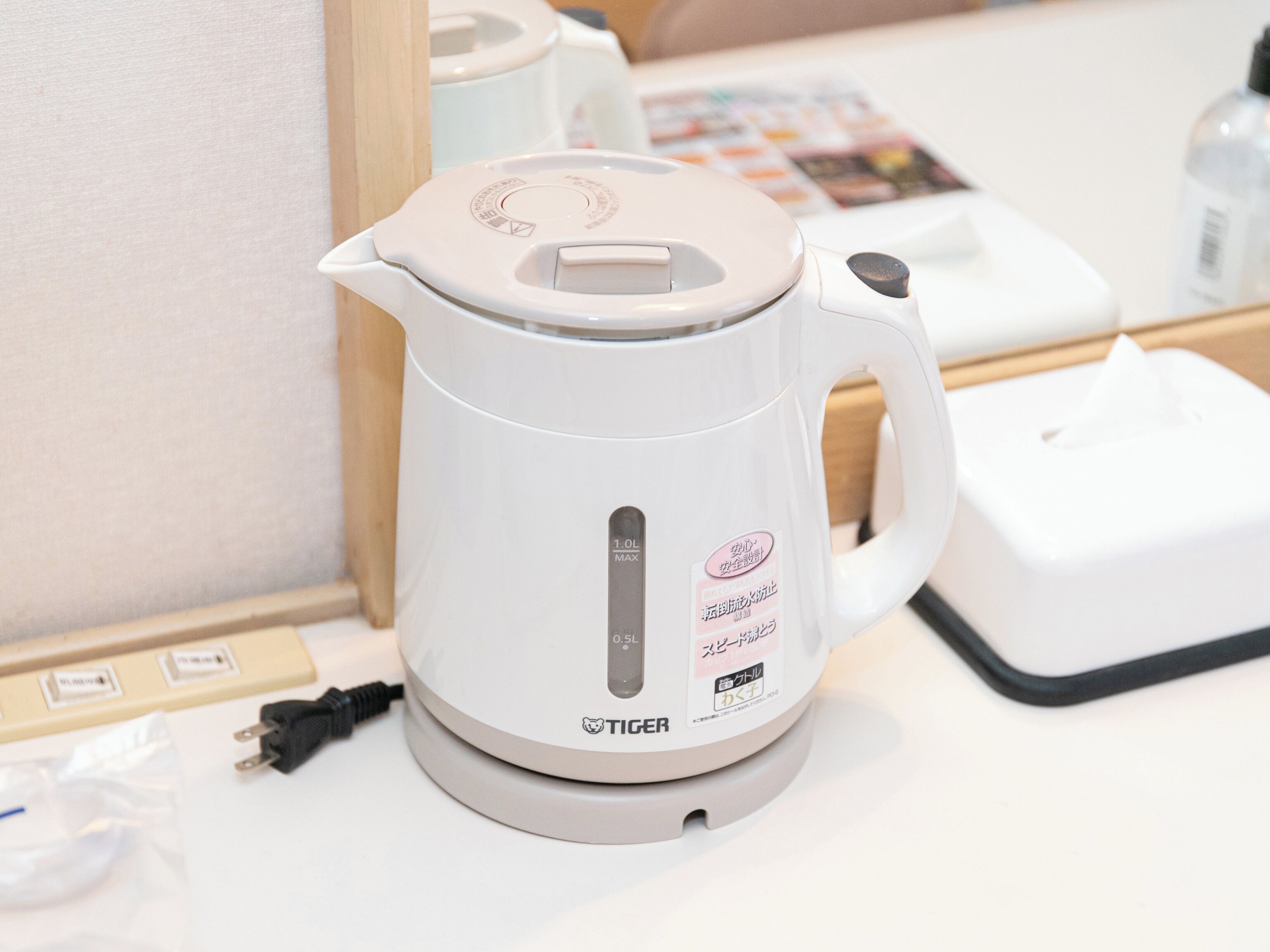A white electric kettle with a digital display and a power cord on a white countertop.