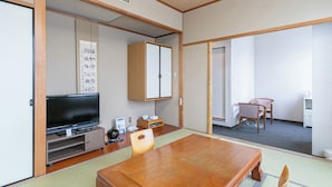 A traditional Japanese room with tatami flooring, a wooden table, a television, and a cabinet. - Hotel Verfort Hyuga (Hyuga)