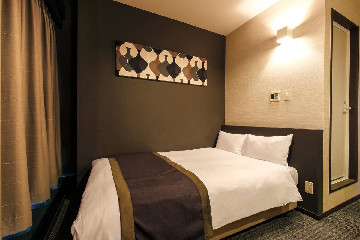 Een hotelkamer met een bed, een kunstwerk aan de muur, een deur en een lamp.