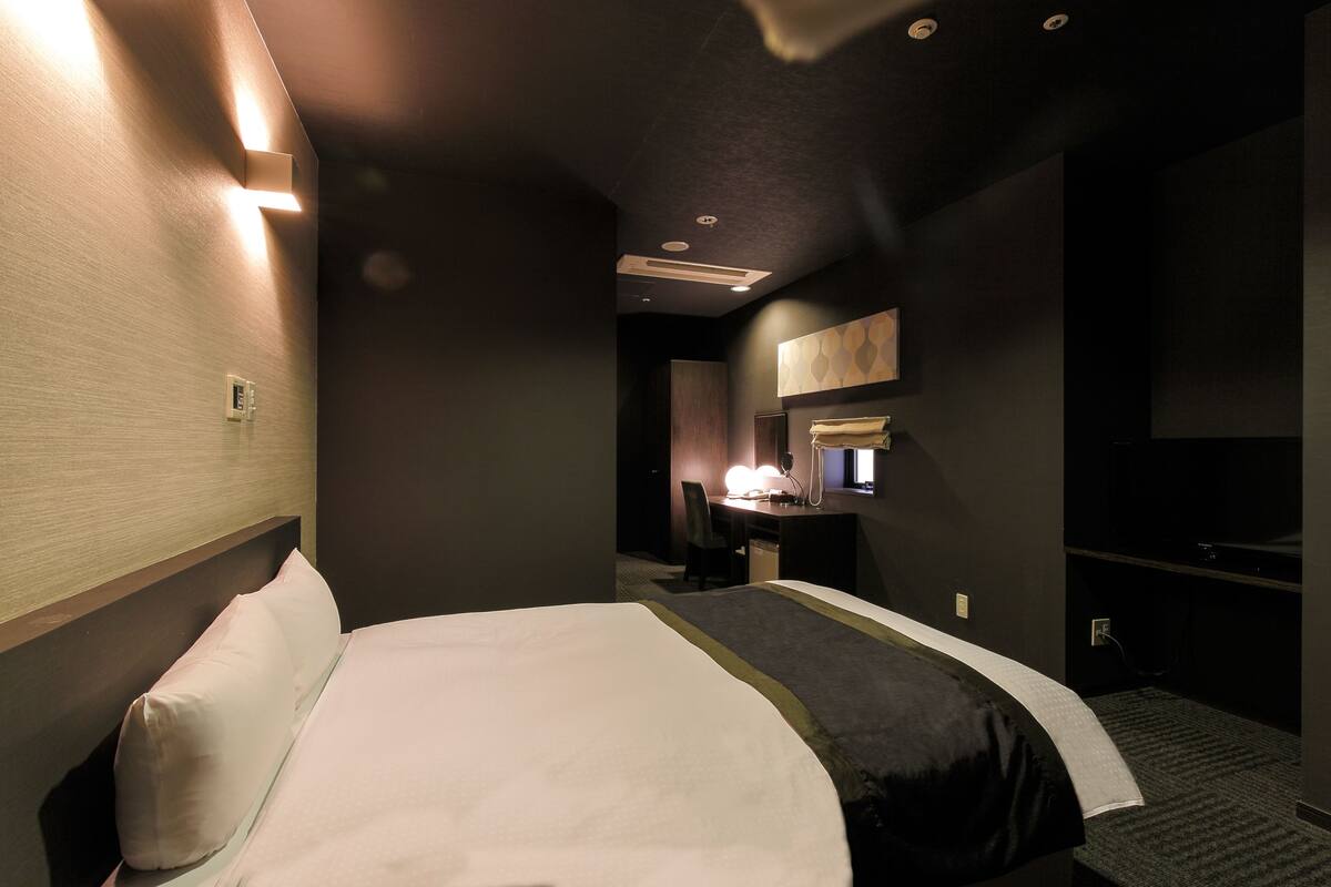 Een hotelkamer met een groot bed, een bureau met stoel, een spiegel en een televisie.