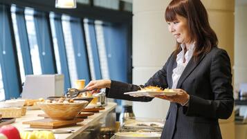 A buffet setup with various food items and a person serving food.