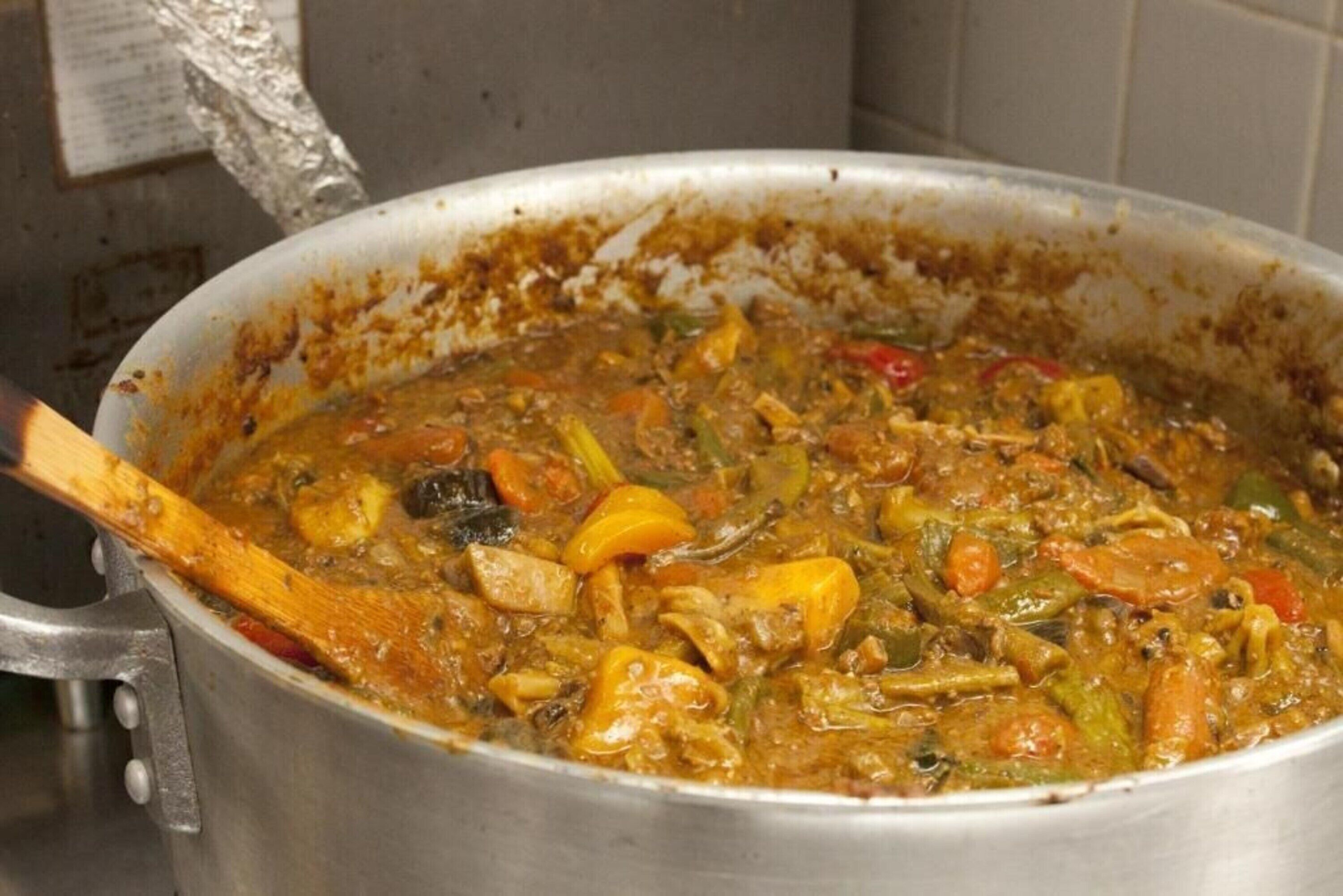 Una olla grande de estofado con carne y diversos vegetales, probablemente en una cocina.
