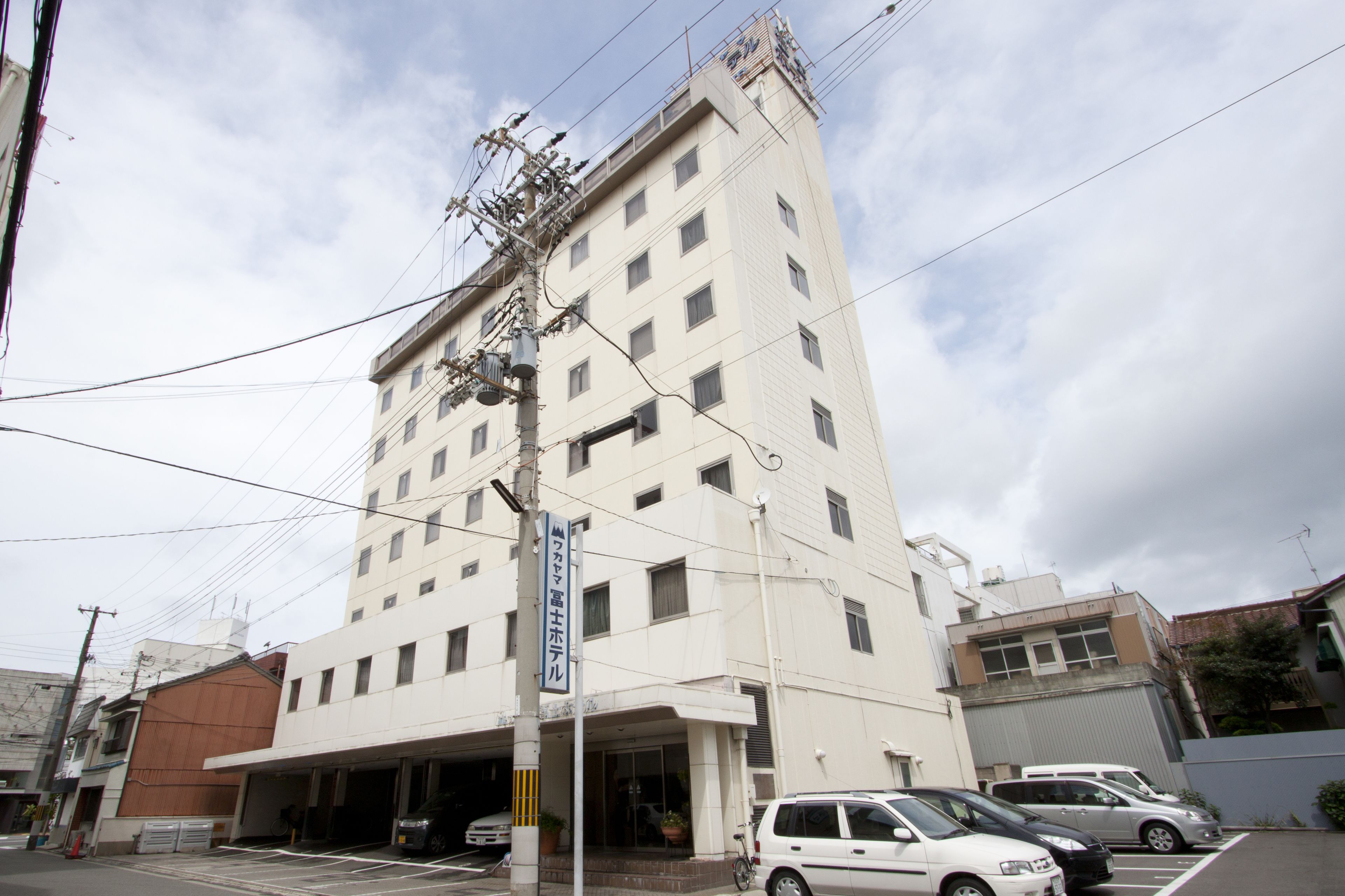 A multi-story hotel with a parking garage and several parked cars.