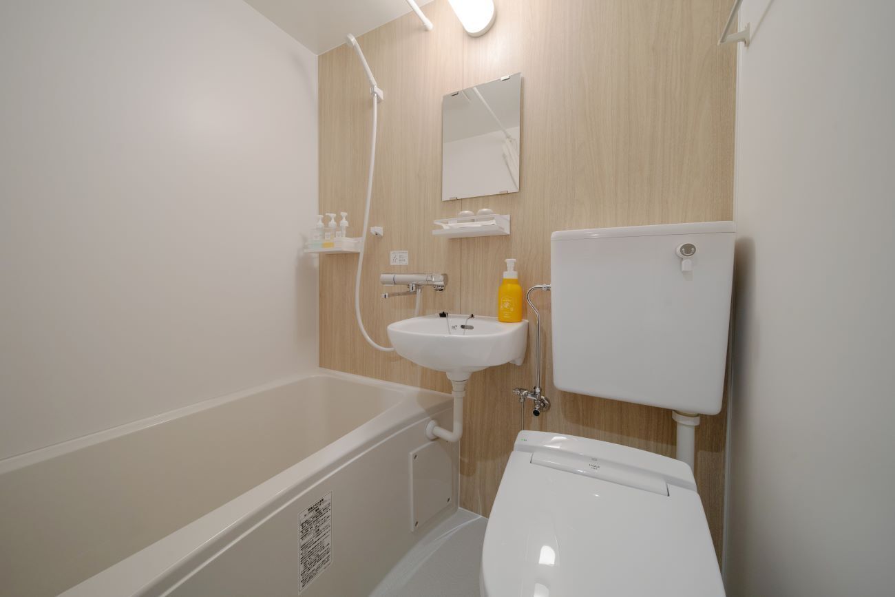A bathroom with a bathtub, sink, mirror, and toilet.