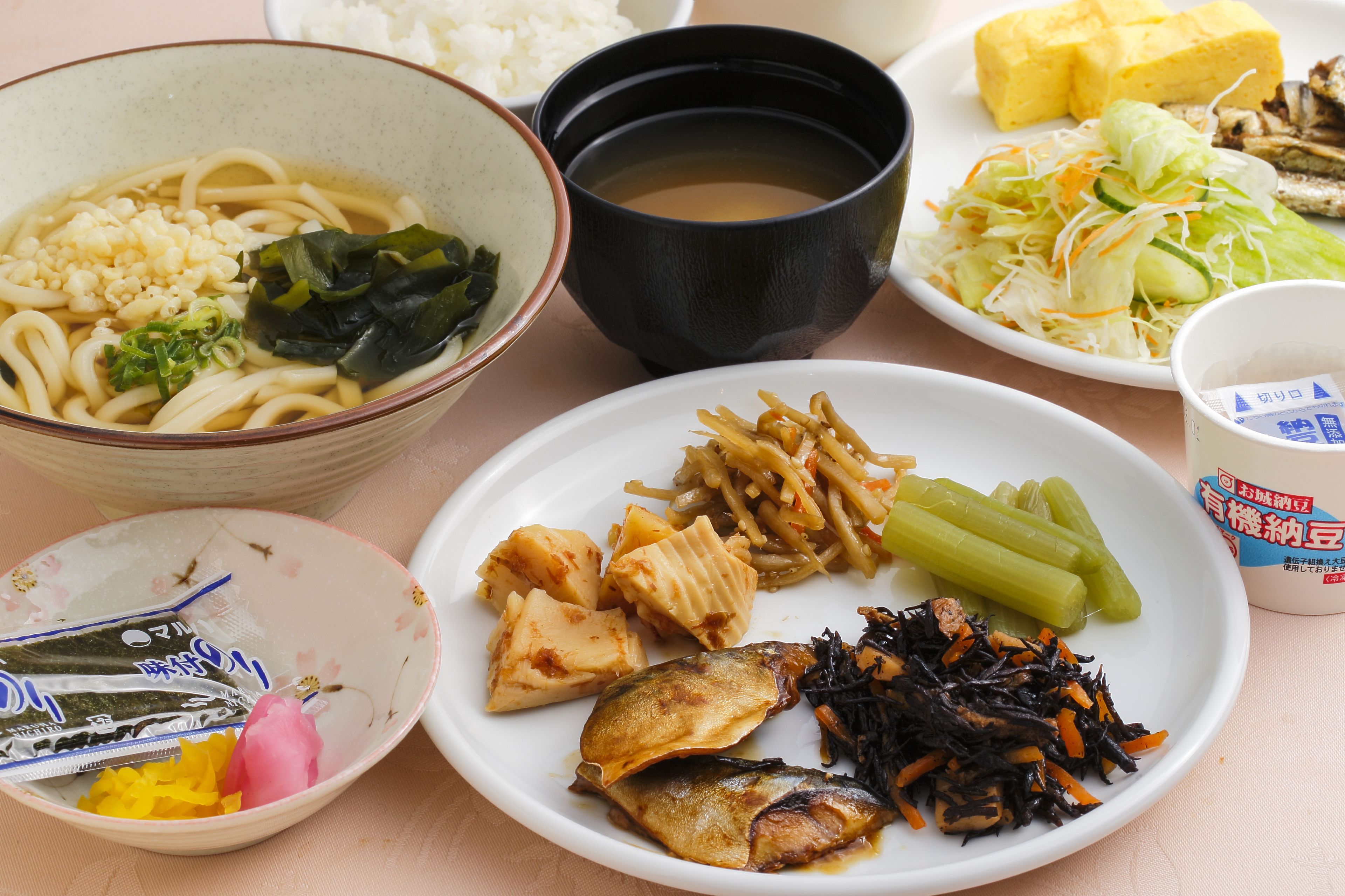 A variety of dishes including noodles, tofu, and vegetables on a table.