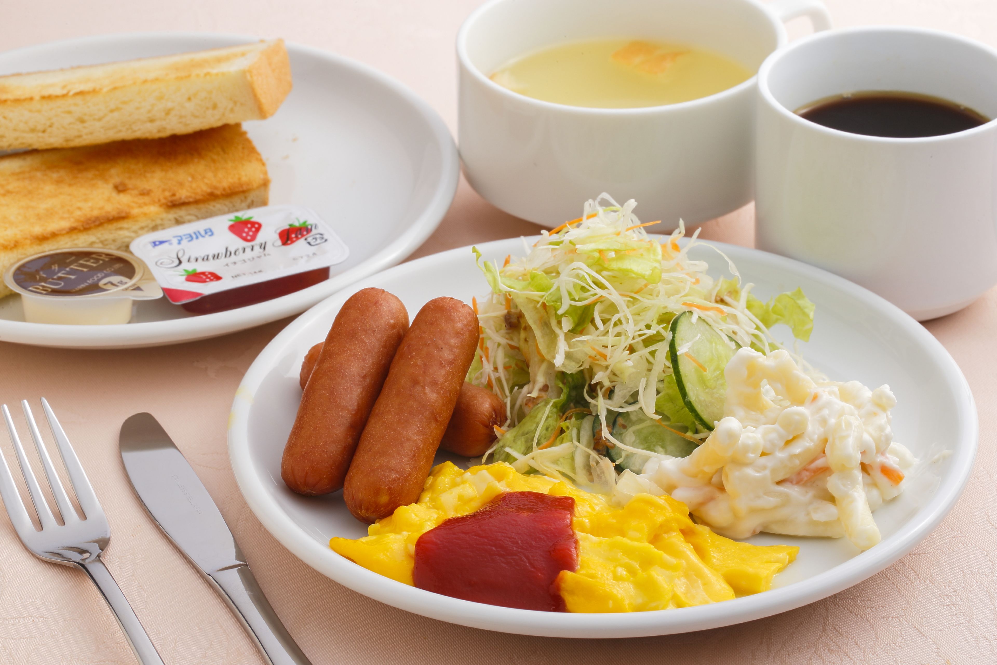 A breakfast plate with sausages, scrambled eggs, and a side salad.