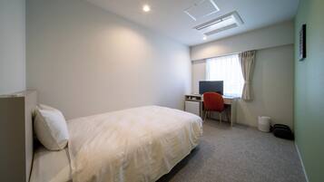 Habitación de hotel con cama, escritorio, silla, ventana con cortinas e iluminación en el techo.
