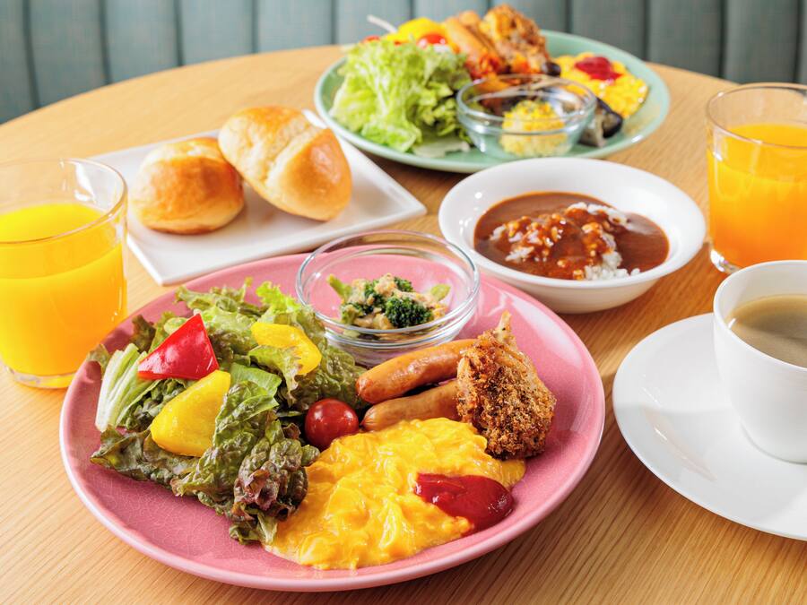 A breakfast setting with plates of food, a glass of orange juice, and a cup of coffee on a wooden table.