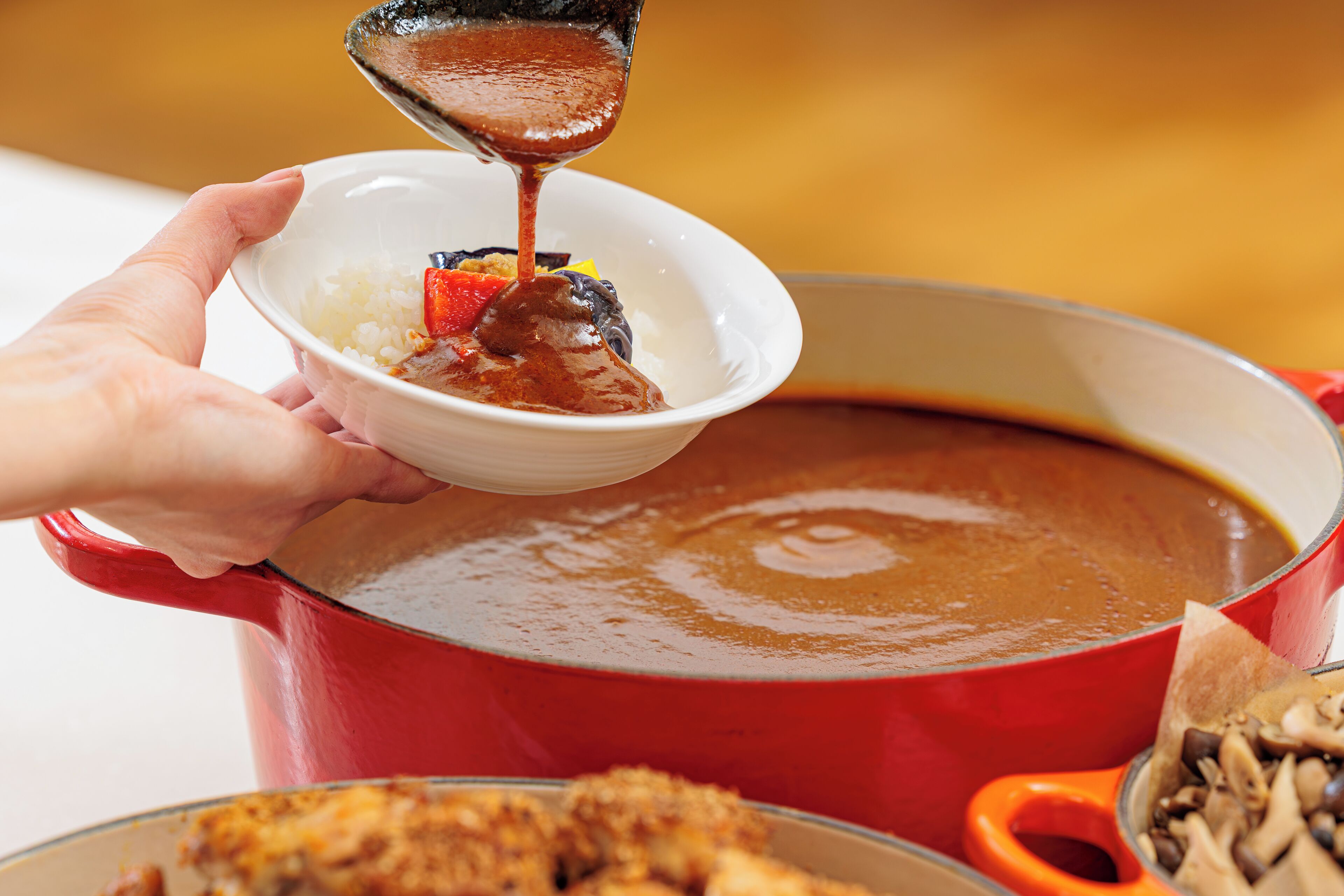 A person pouring a brown sauce into a bowl containing rice and vegetables.