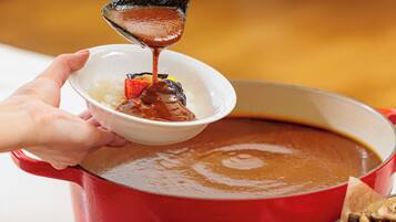 A person pouring a brown sauce into a bowl containing rice and vegetables.