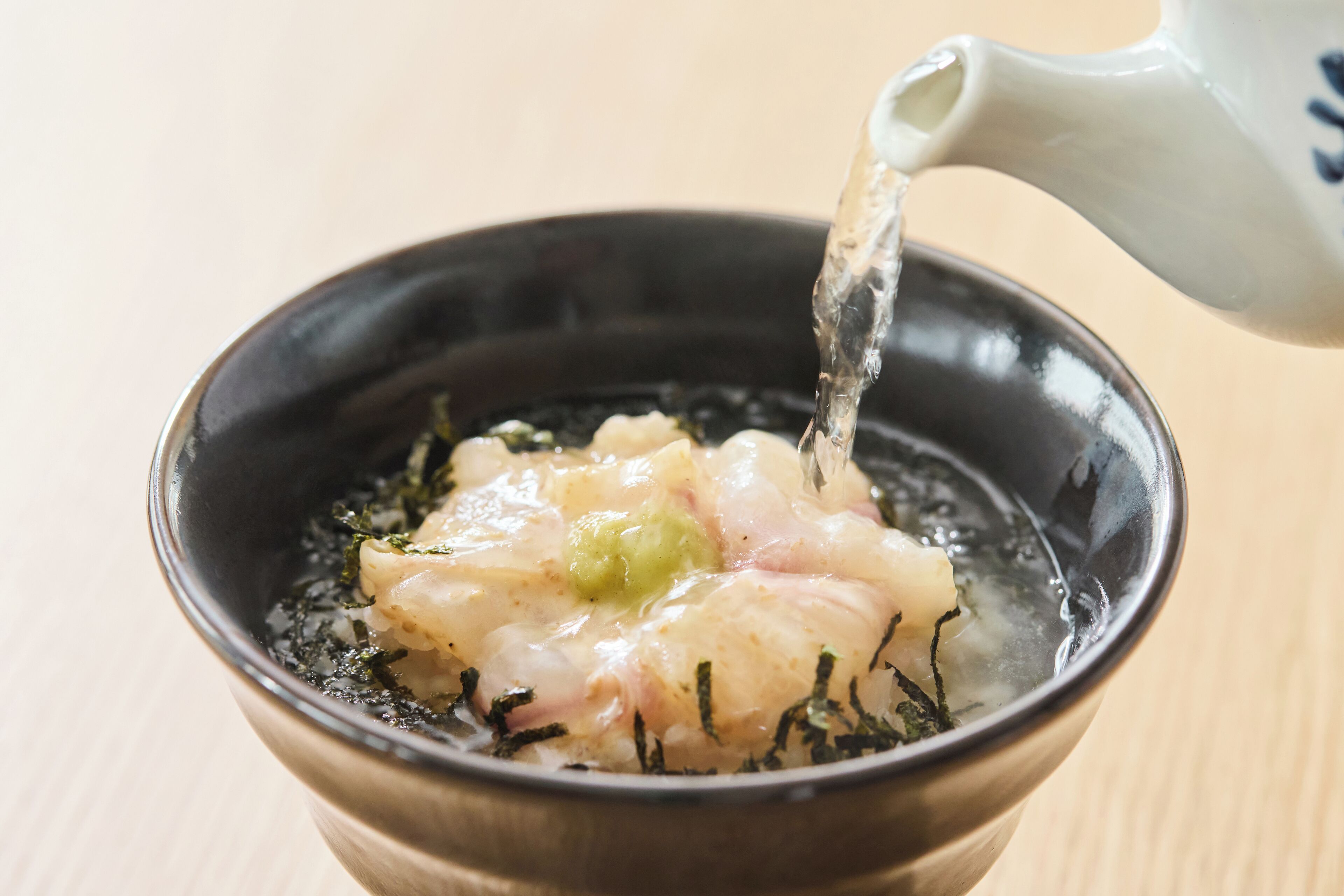 A bowl of food with a liquid being poured into it.