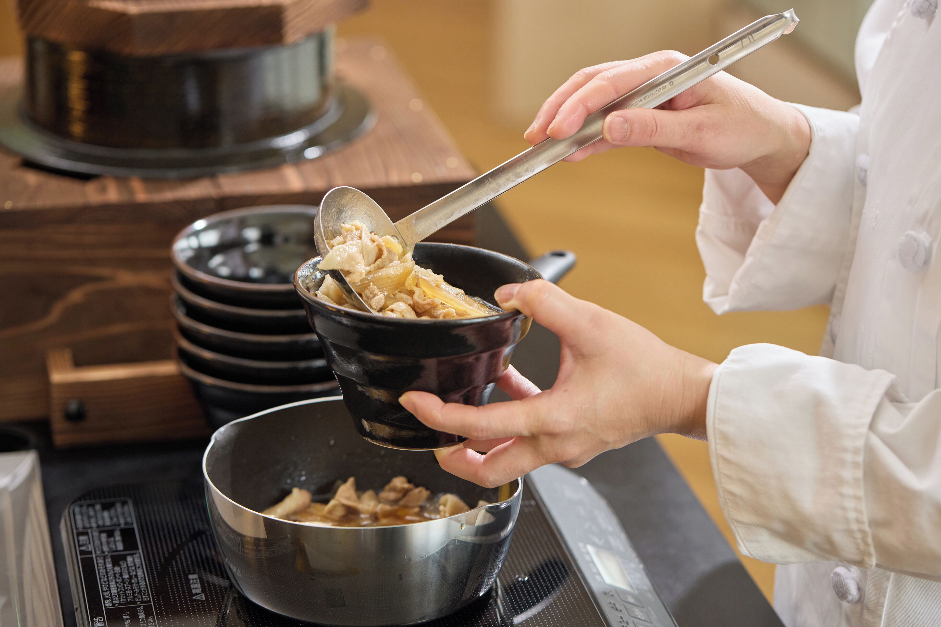 Une personne qui cuisine avec une cuillère dans un bol, sur une cuisinière.