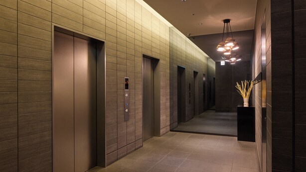 Un couloir moderne doté d’ascenseurs et d’un luminaire décoratif.