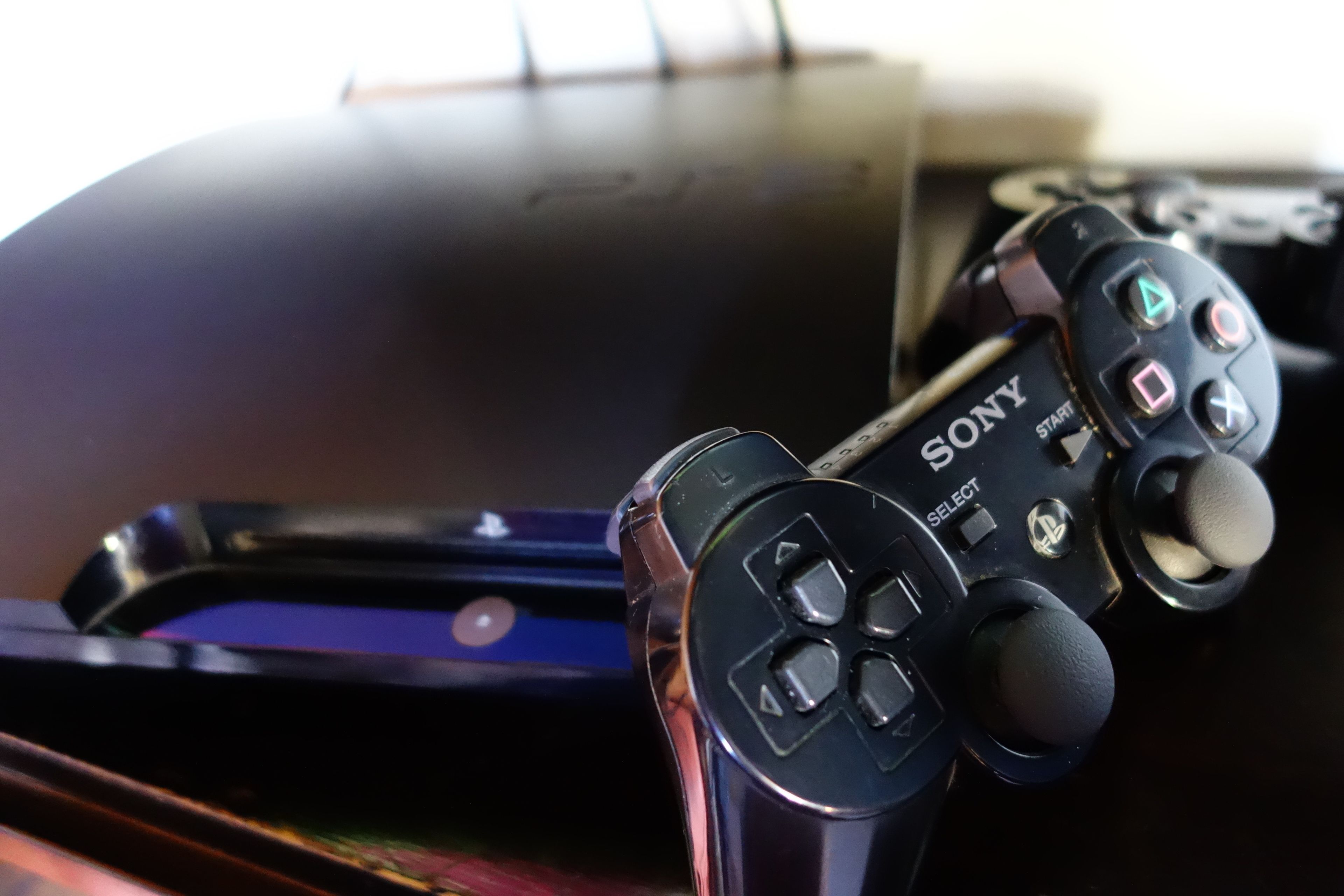 A close-up of a Sony PlayStation controller with a black and silver design, resting on a surface.