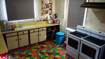 Een keuken met een vloer in verschillende kleuren, een spoelbak, kastjes, een fornuis en een raam.