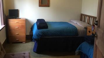 A bedroom with a bed, a dresser, a chair, and a mirror on the wall.