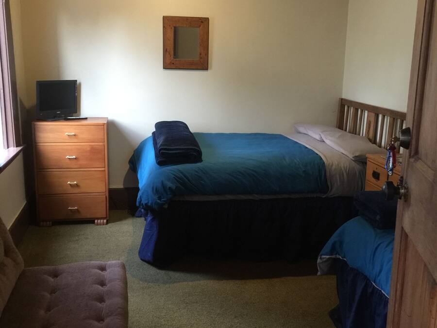 A bedroom with a bed, a dresser, a chair, and a mirror on the wall.