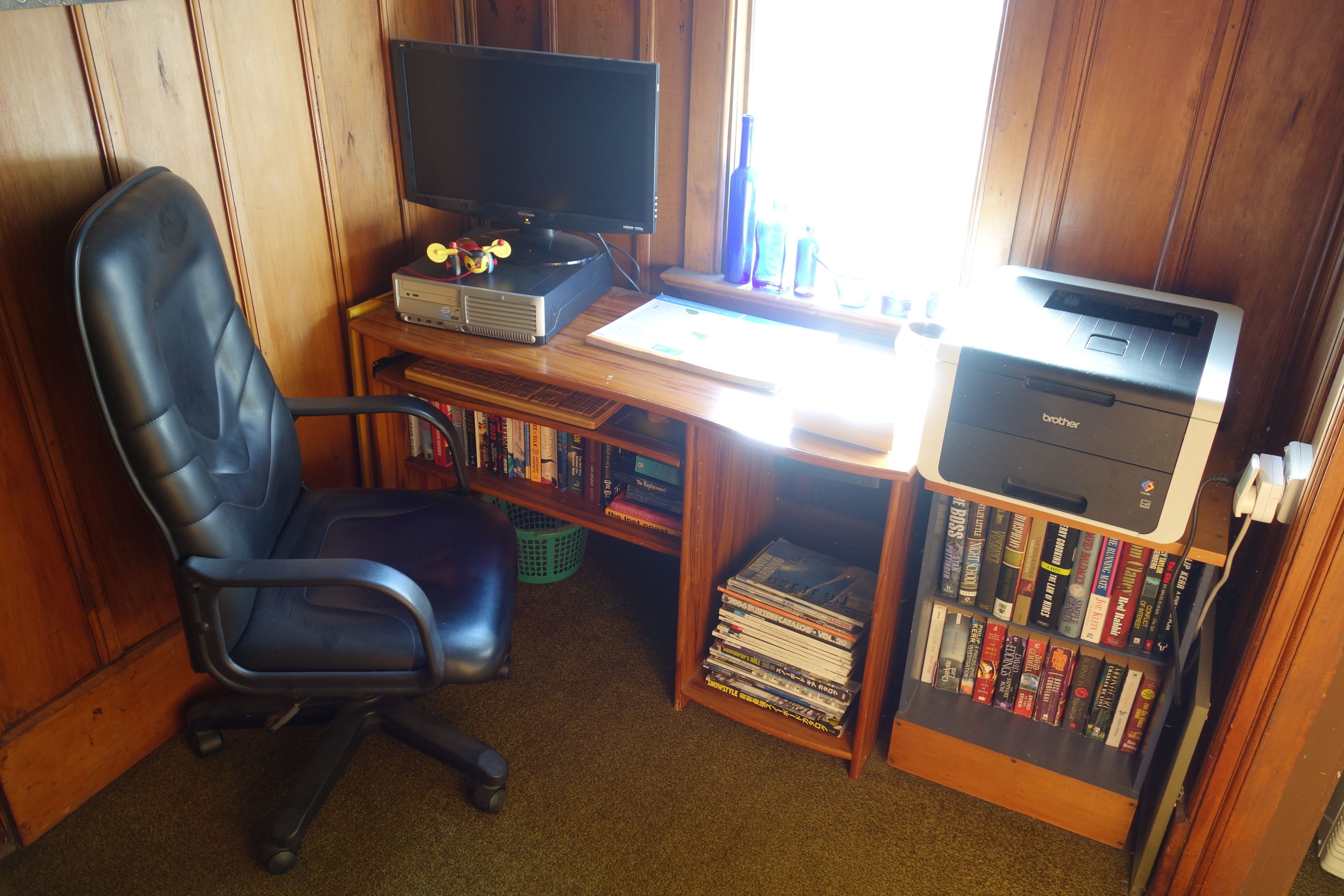 A home office setup with a computer, printer, and a bookshelf filled with books.
