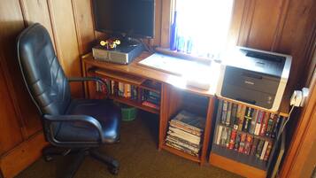 A home office setup with a computer, printer, and a bookshelf filled with books.