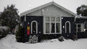 A house with a sloped roof, a chimney, and a snow-covered landscape. - Big Tree Lodge Methven - Hostel (Methven)